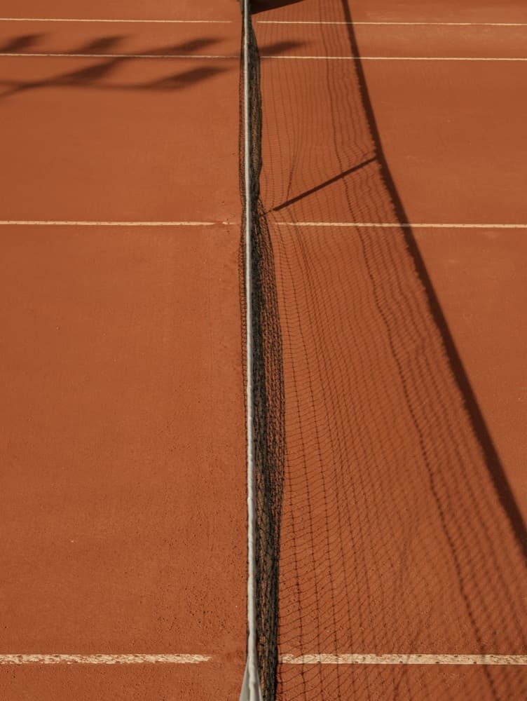The net and white lines stretched taut across the red clay of Court A